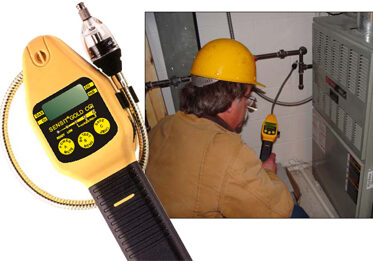 A man using a gas detector while wearing a yellow hard hat.
