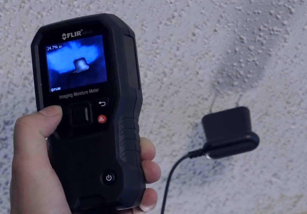 A person holding a thermal imaging camera showing a blue heat pattern.